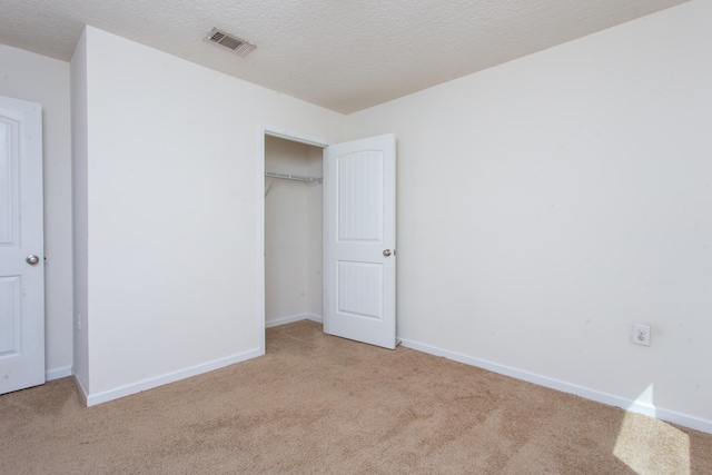 unfurnished bedroom with visible vents, a closet, carpet, and a textured ceiling
