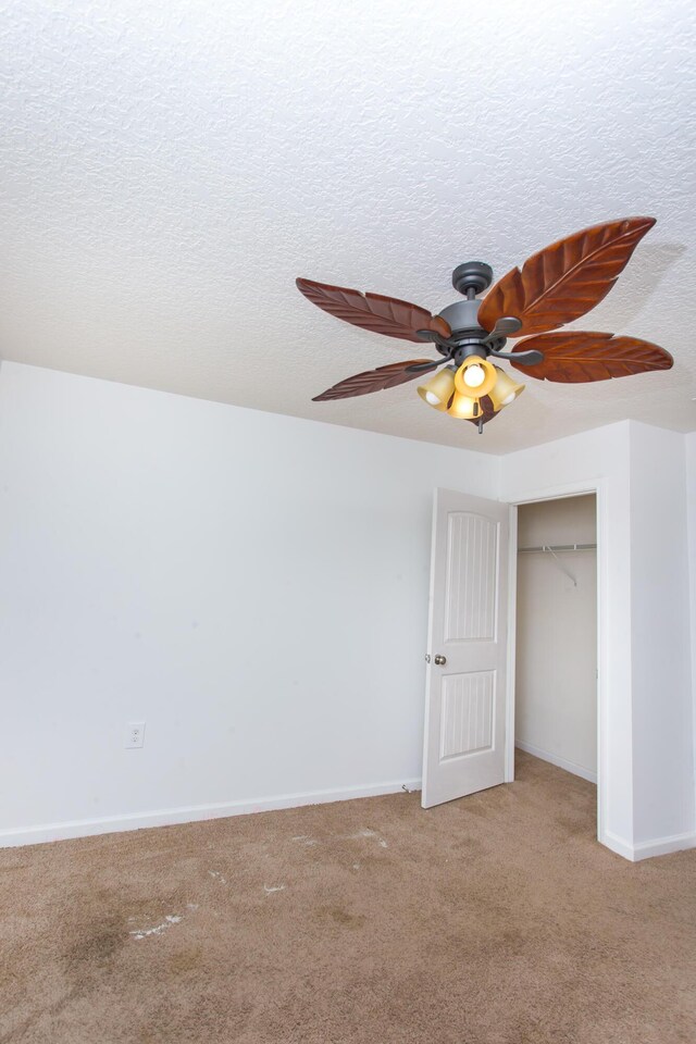 unfurnished bedroom featuring carpet flooring, baseboards, a textured ceiling, a ceiling fan, and a closet