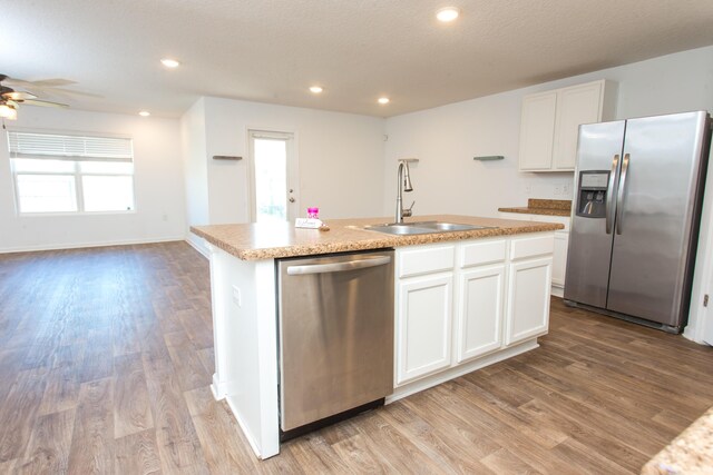 kitchen with an island with sink, white cabinetry, a sink, and stainless steel appliances