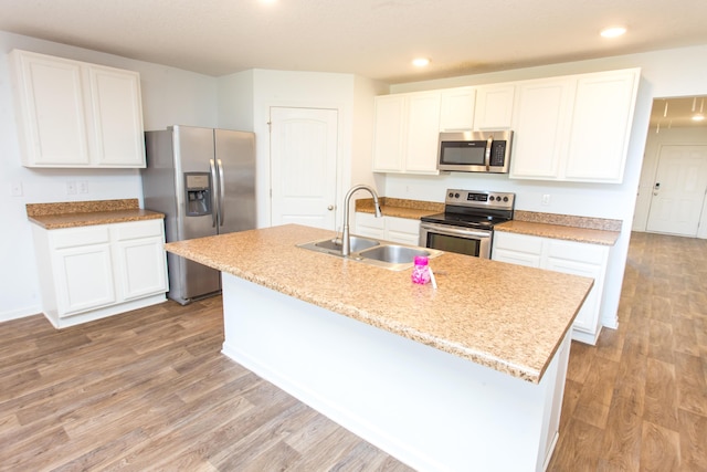 kitchen with a sink, white cabinets, light wood-style floors, and appliances with stainless steel finishes