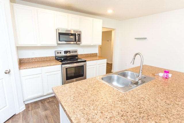 kitchen with light countertops, a sink, white cabinetry, wood finished floors, and appliances with stainless steel finishes