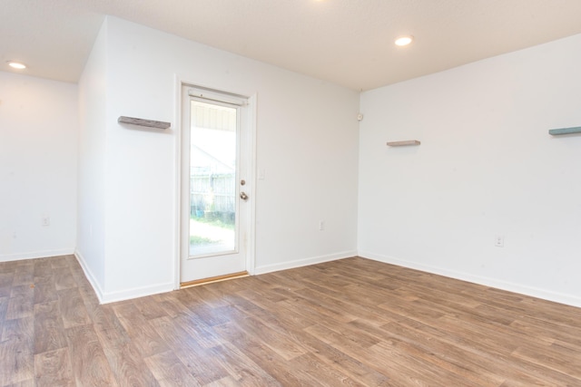 spare room featuring recessed lighting, baseboards, and wood finished floors
