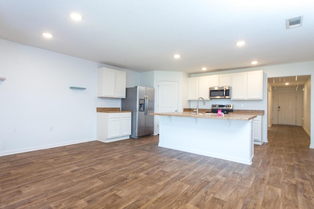 kitchen with appliances with stainless steel finishes, a center island with sink, dark wood-style floors, white cabinets, and recessed lighting