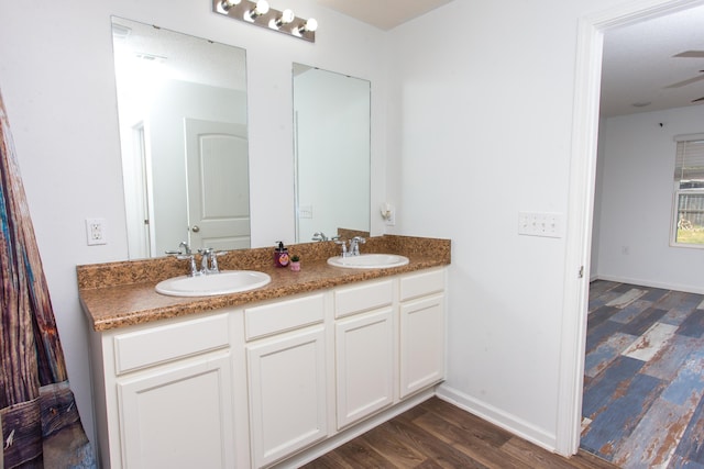 full bathroom with double vanity, wood finished floors, baseboards, and a sink