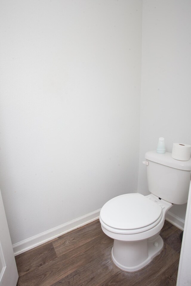 bathroom with toilet, baseboards, and wood finished floors