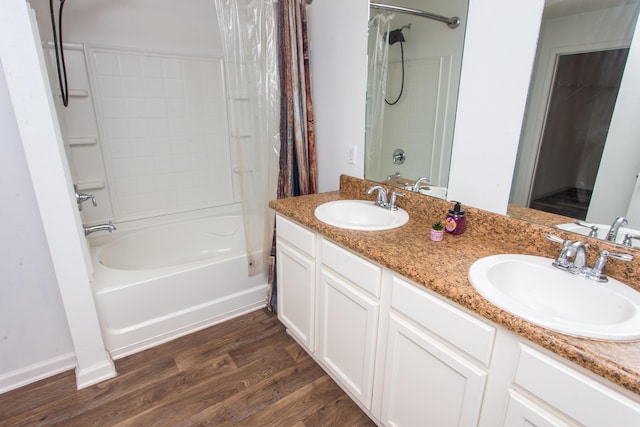 full bath with shower / bath combination with curtain, double vanity, a sink, and wood finished floors