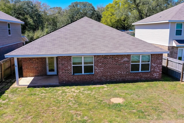 back of property with brick siding, fence, a yard, and a patio area