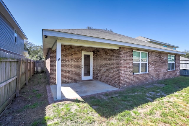 rear view of house featuring a fenced backyard, brick siding, a yard, and a patio