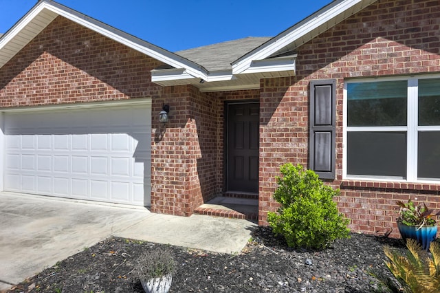 doorway to property with brick siding, driveway, and an attached garage