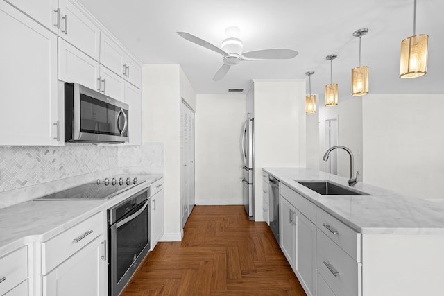 kitchen featuring light stone countertops, a sink, stainless steel appliances, white cabinets, and backsplash