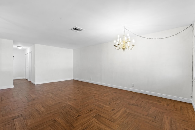 spare room with visible vents, an inviting chandelier, and baseboards