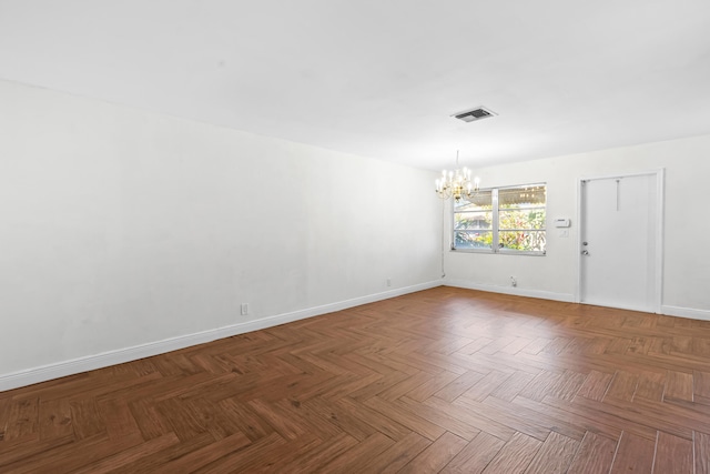 spare room featuring a chandelier, visible vents, and baseboards