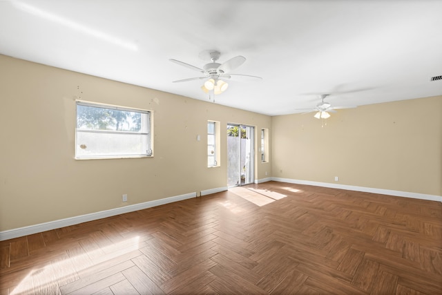 unfurnished room with visible vents, a ceiling fan, and baseboards