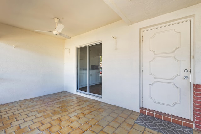 entrance to property featuring stucco siding, ceiling fan, and a patio area