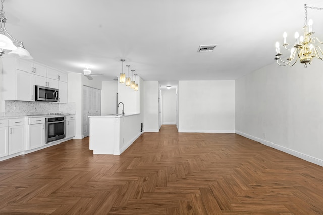 kitchen featuring visible vents, open floor plan, ceiling fan with notable chandelier, stainless steel appliances, and white cabinetry