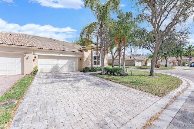 view of front of house with a garage, decorative driveway, a tile roof, and stucco siding