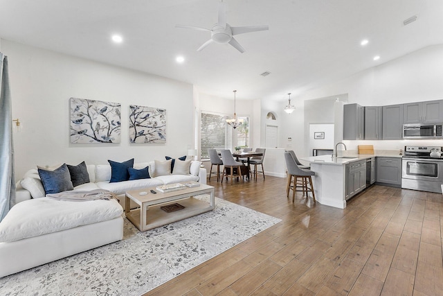 living room featuring ceiling fan with notable chandelier, dark wood-style flooring, visible vents, and recessed lighting