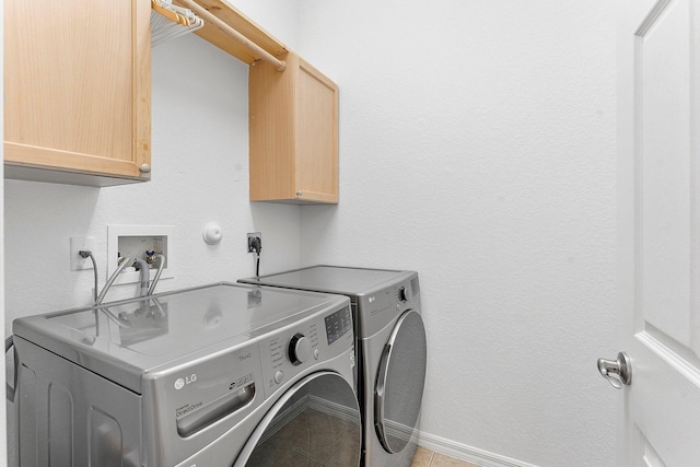 clothes washing area with light tile patterned floors, cabinet space, baseboards, and separate washer and dryer