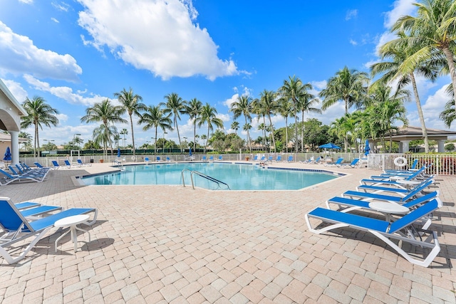 community pool with a patio and fence