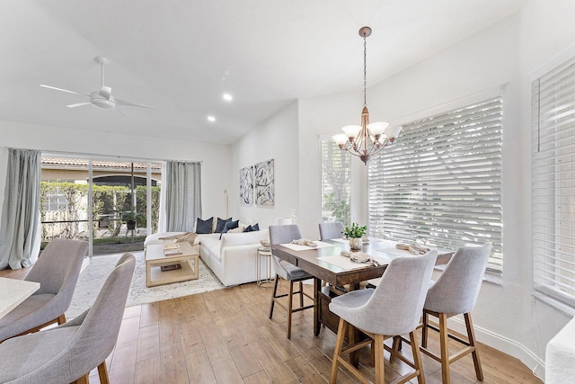 dining space with vaulted ceiling, ceiling fan with notable chandelier, light wood-type flooring, and recessed lighting