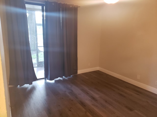 spare room with dark wood-style flooring and baseboards