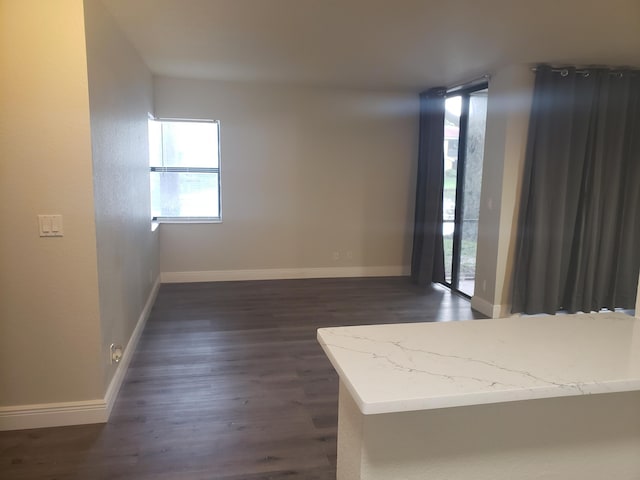 unfurnished room featuring baseboards and dark wood-style flooring