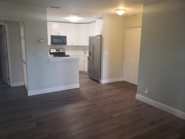 kitchen featuring dark wood-style flooring, light countertops, appliances with stainless steel finishes, white cabinets, and baseboards