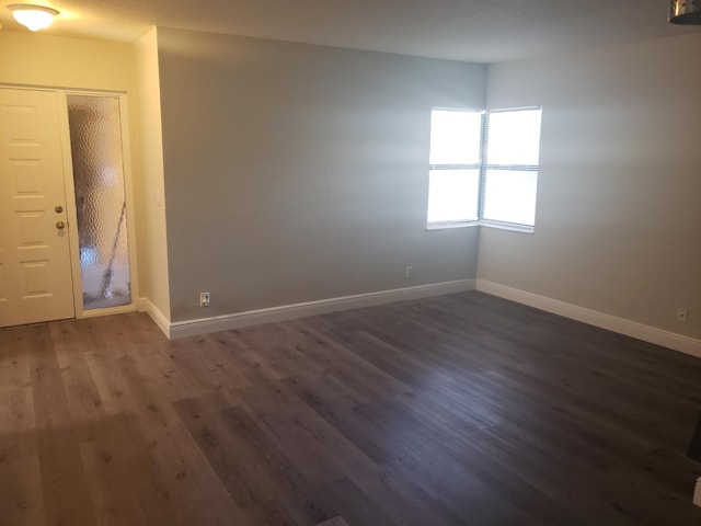 unfurnished room with dark wood finished floors and baseboards