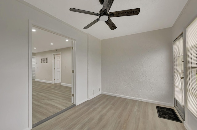 unfurnished room with baseboards, a textured wall, visible vents, and light wood-style floors