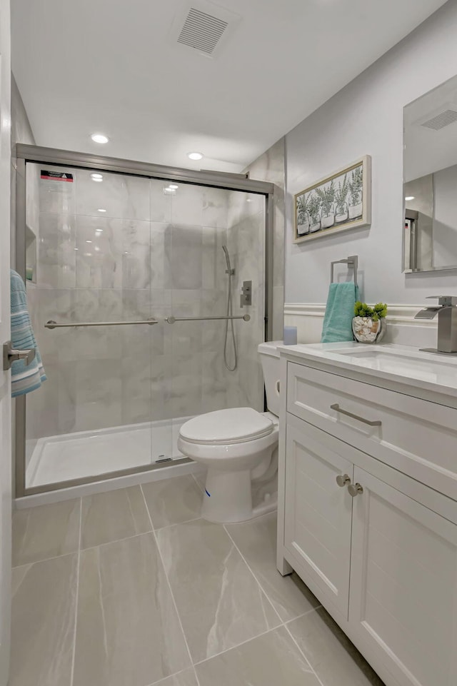 bathroom with toilet, vanity, visible vents, and a shower stall