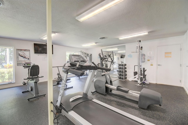 exercise room featuring a textured ceiling, a wealth of natural light, and baseboards