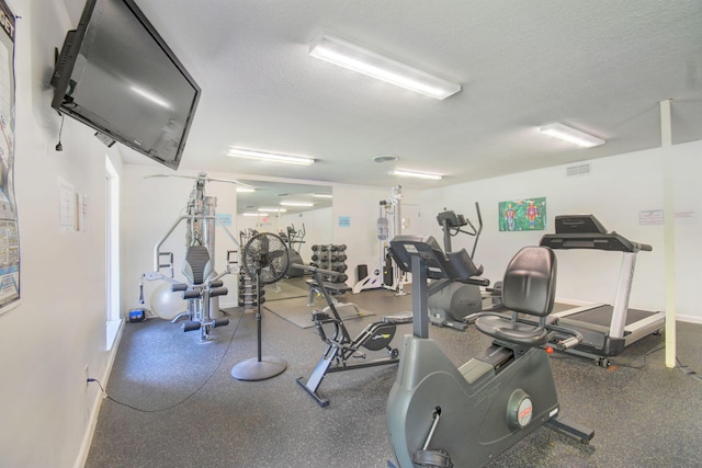 gym with visible vents, a textured ceiling, and baseboards