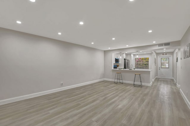 unfurnished living room featuring light wood-type flooring, visible vents, baseboards, and recessed lighting