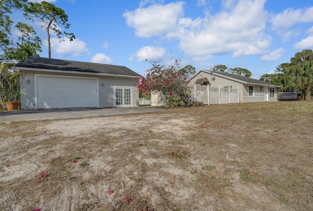 view of front of house with fence, french doors, a garage, and stucco siding