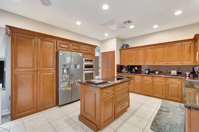 kitchen with stainless steel appliances, light tile patterned floors, visible vents, and dark stone countertops