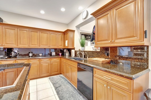 kitchen with light tile patterned floors, dark stone counters, decorative backsplash, dishwashing machine, and a sink