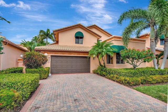 mediterranean / spanish home with a tiled roof, decorative driveway, and stucco siding