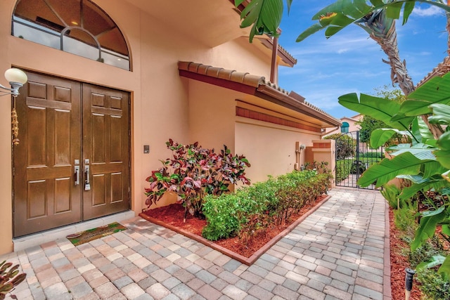 doorway to property featuring stucco siding and a gate