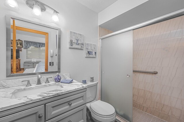 ensuite bathroom featuring a shower stall, toilet, vanity, and connected bathroom