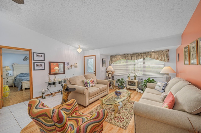 living room featuring light tile patterned floors, lofted ceiling, and a textured ceiling