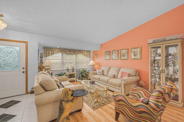 living area featuring vaulted ceiling, light wood-style flooring, and a textured ceiling