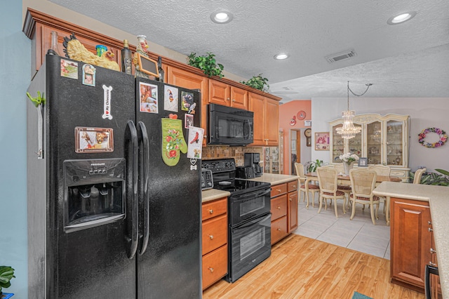 kitchen featuring brown cabinetry, visible vents, black appliances, light countertops, and light wood-style floors