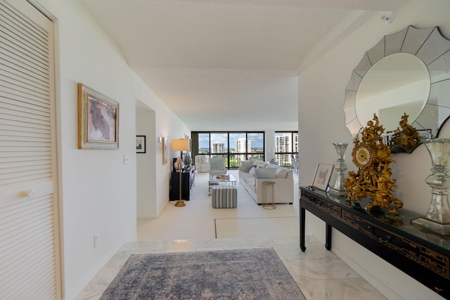 corridor featuring expansive windows, marble finish floor, and baseboards