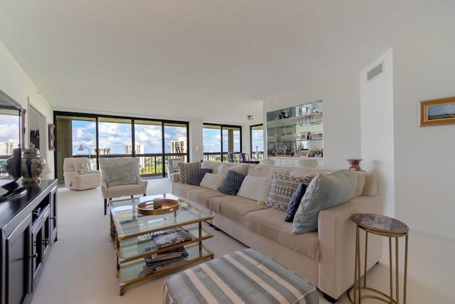 living area featuring carpet floors, floor to ceiling windows, visible vents, and a textured ceiling