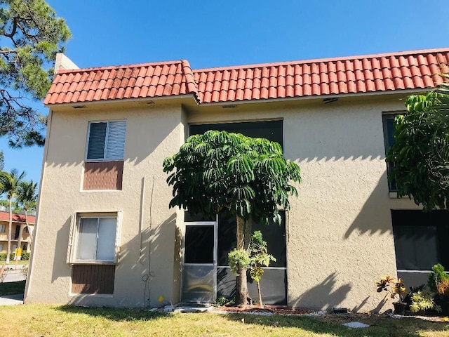 back of house featuring a tile roof and stucco siding