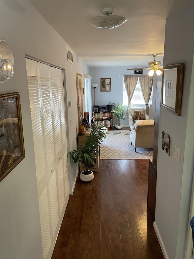 hallway featuring dark wood-style flooring, visible vents, and baseboards