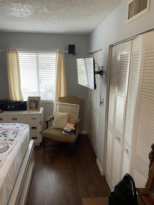 bedroom featuring dark wood-style floors, two closets, visible vents, a textured ceiling, and baseboards