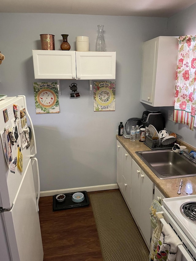 kitchen featuring wood finished floors, white appliances, a sink, and white cabinetry