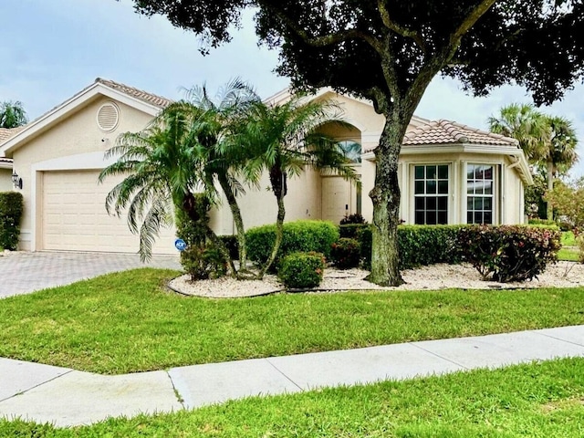 view of front of home featuring a garage, a tile roof, decorative driveway, stucco siding, and a front lawn