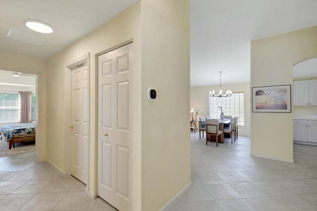 corridor with light tile patterned floors, baseboards, and a chandelier